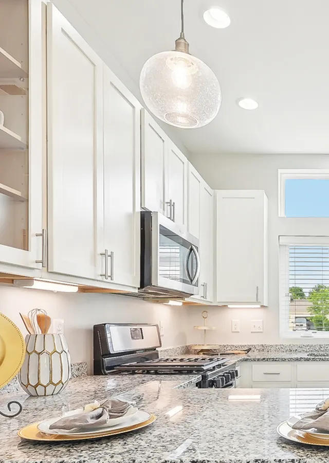 Kitchen with white shaker cabinets, stainless appliances, on-trend lighting and hardware and bright, natural lighting