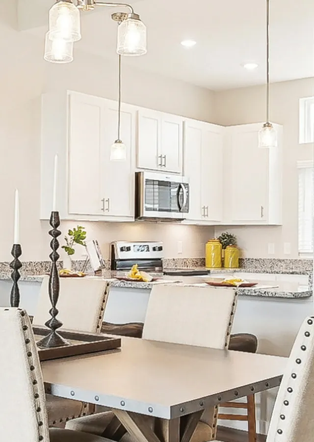 Modern kitchen with sleek white cabinets, stylish pendant lighting, and a chic dining area perfect for entertaining.