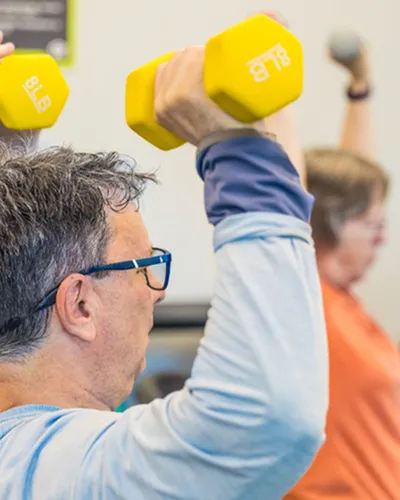 Vibrant fitness class with participants lifting colorful dumbbells, promoting health and vitality.