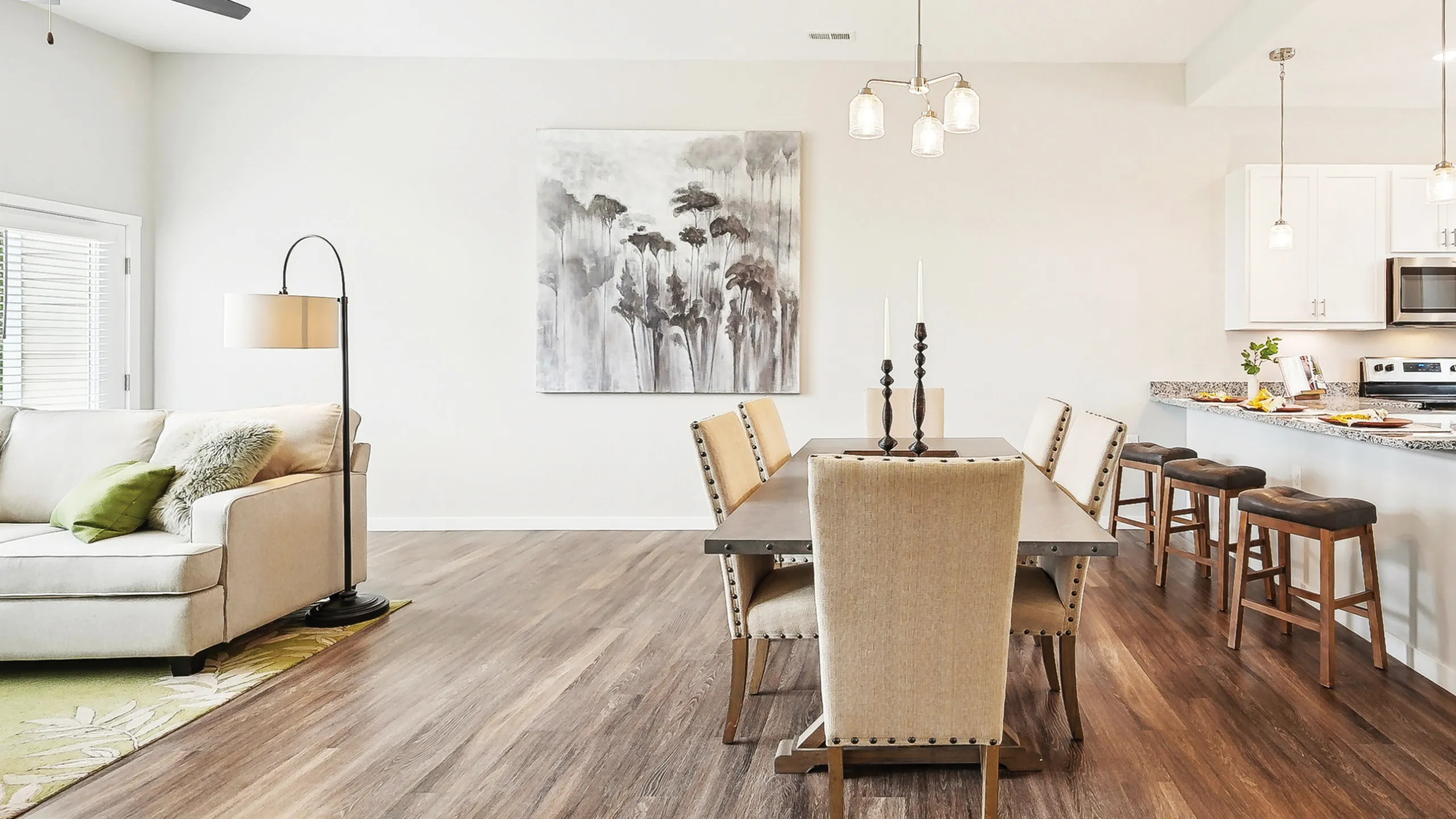 Modern open-concept living and dining area featuring elegant decor and stylish kitchen bar with high-top seating.