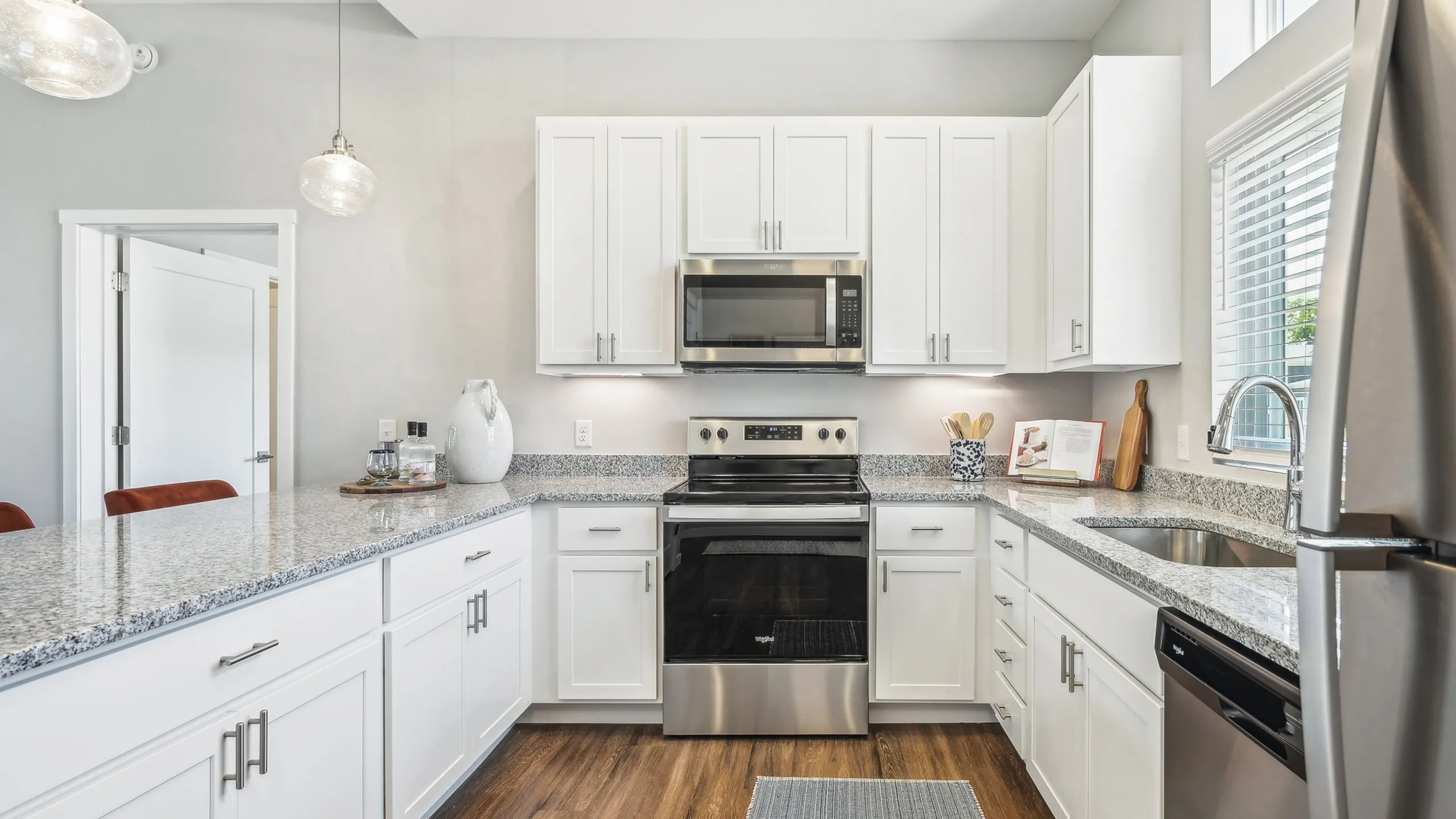 Bright and modern kitchen with sleek granite countertops, white cabinetry, and stainless steel appliances, perfect for culinary enthusiasts.