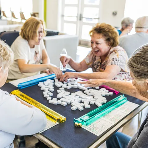 Vibrant group enjoying a lively game of dominoes in a bright and welcoming community space.