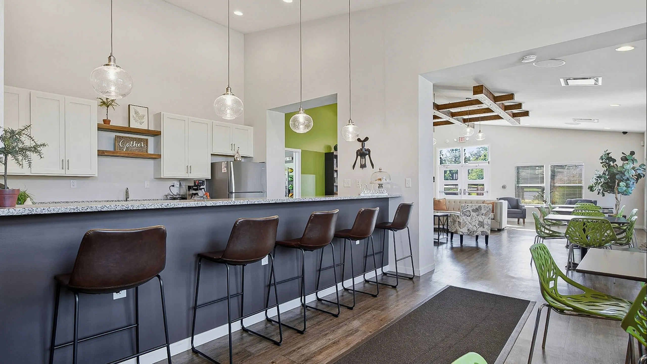 Chic open-concept kitchen and lounge space with elegant pendant lighting, modern bar seating, and inviting natural light.