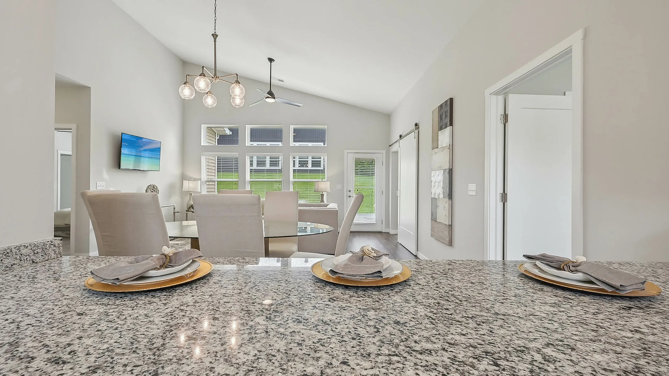 Modern open-concept living area with stylish granite countertop, elegant dining set, and contemporary lighting, offering a bright and inviting atmosphere.