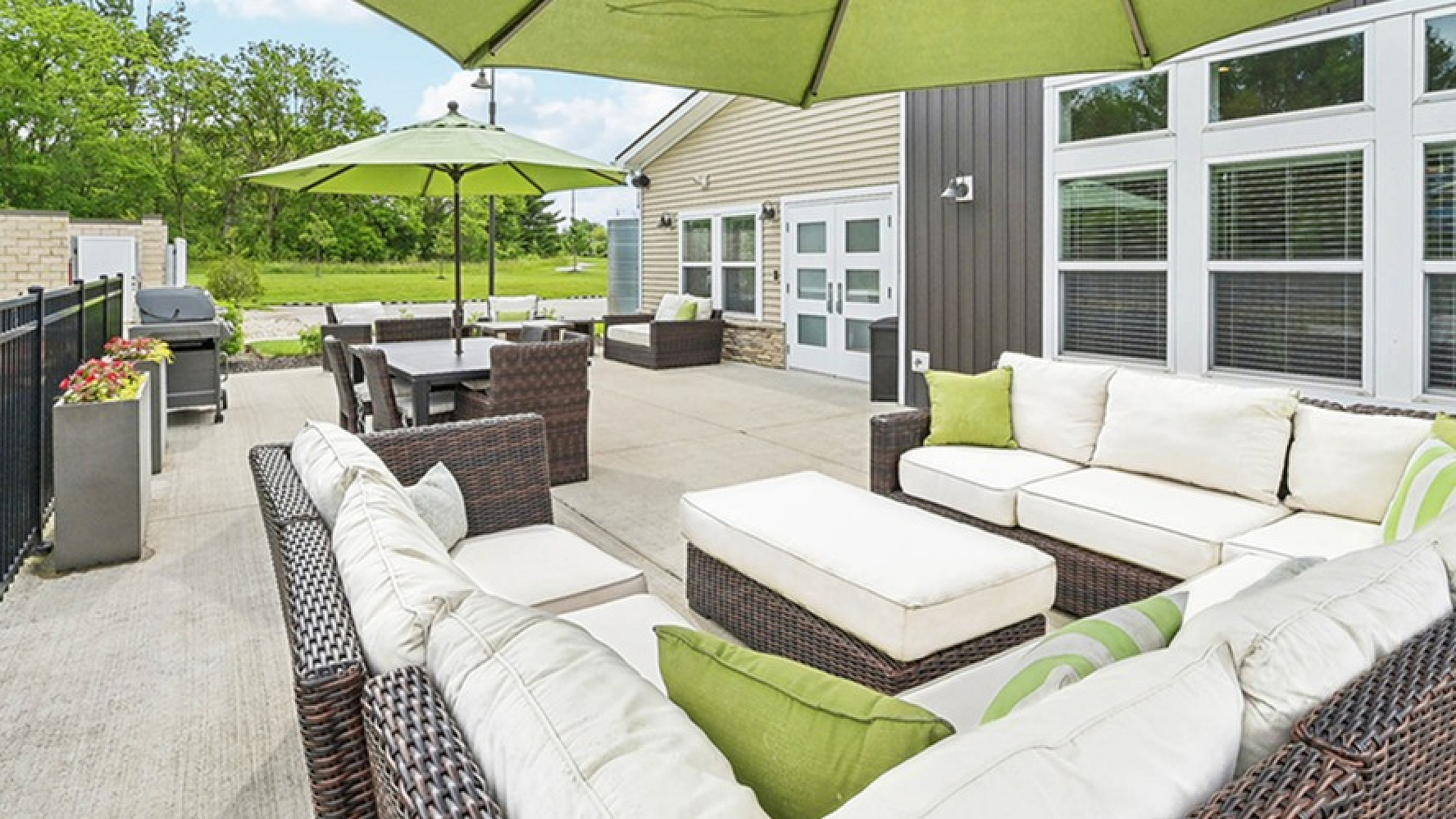 Chic outdoor patio with comfortable wicker furniture and vibrant green umbrellas, perfect for entertaining and relaxation.