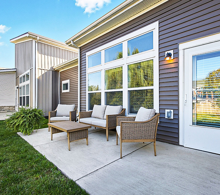 Inviting patio space with modern wicker furniture set against a stylish exterior, perfect for relaxation and outdoor entertaining.