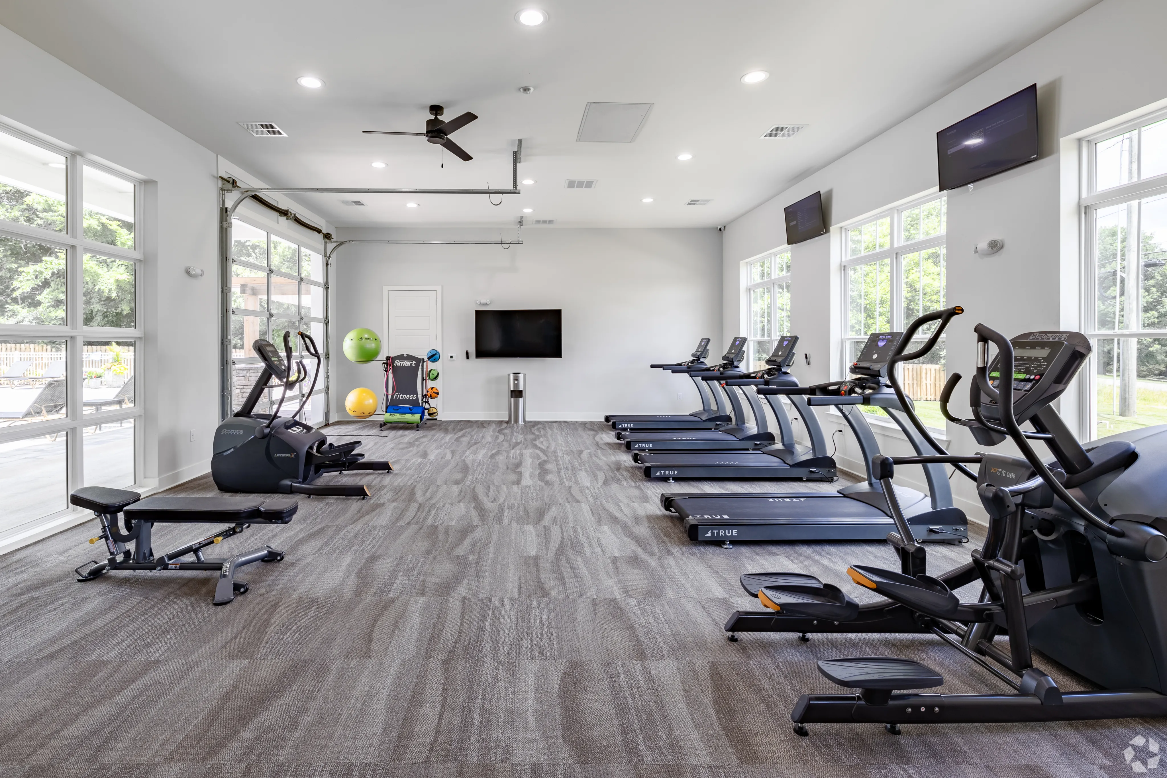 Modern and spacious fitness center with multiple treadmills, exercise machines, and vibrant natural light creating an inviting workout environment.