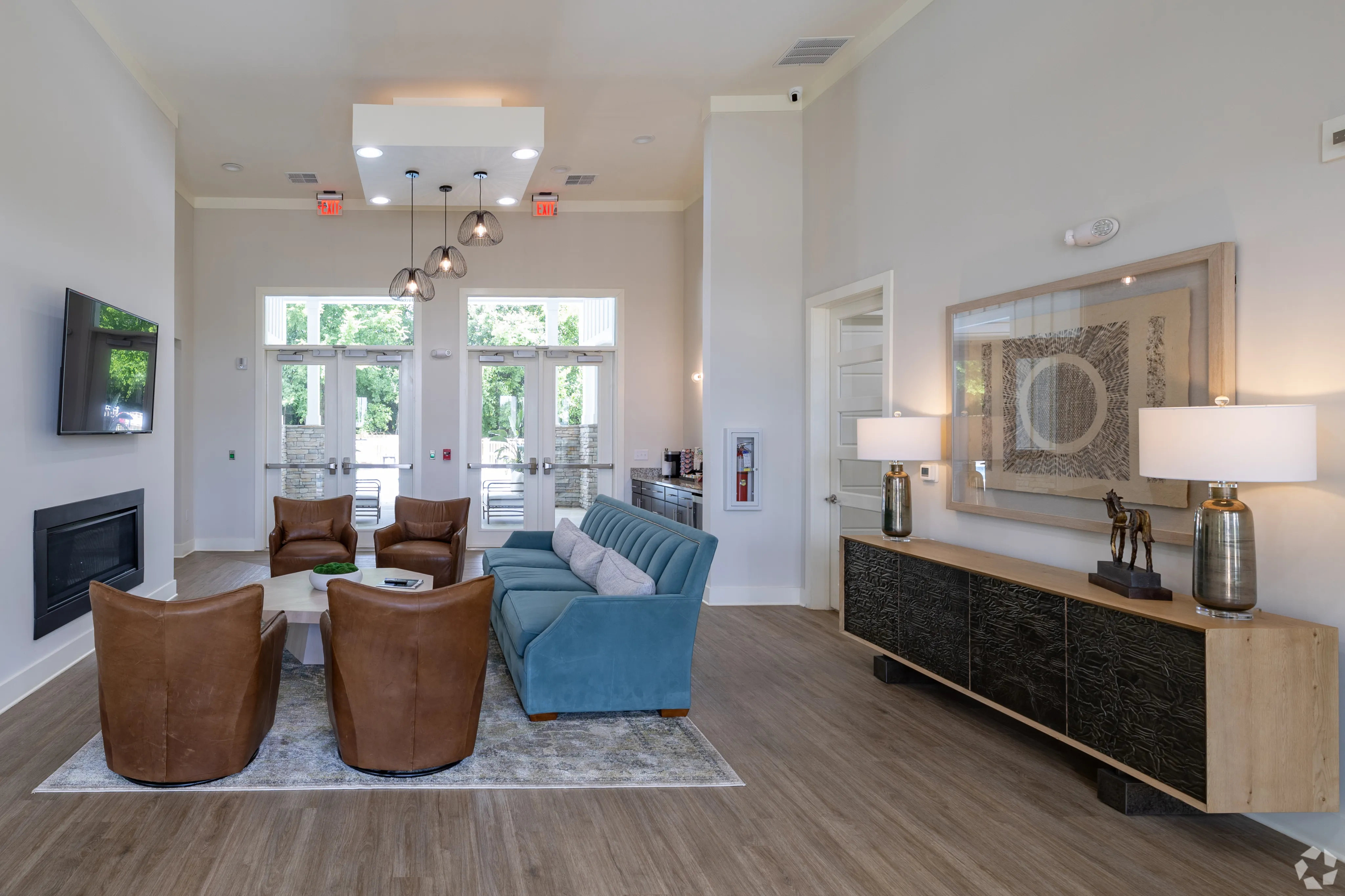 Chic apartment lounge featuring modern decor, plush seating, and a stylish TV area with natural light pouring in through large windows.