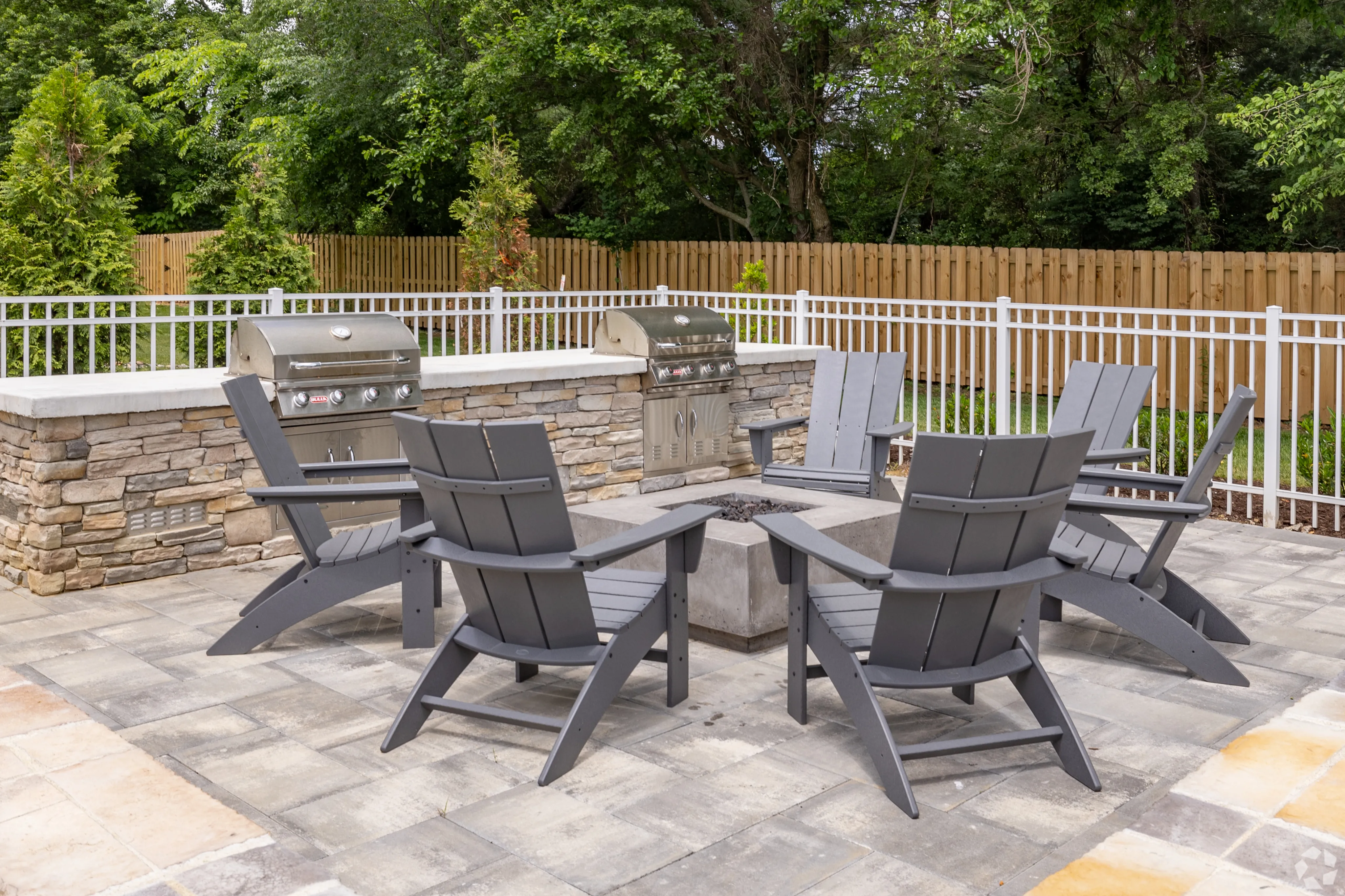 Inviting outdoor patio with chairs surrounding a cozy fire pit, perfect for gatherings, featuring built-in grills.