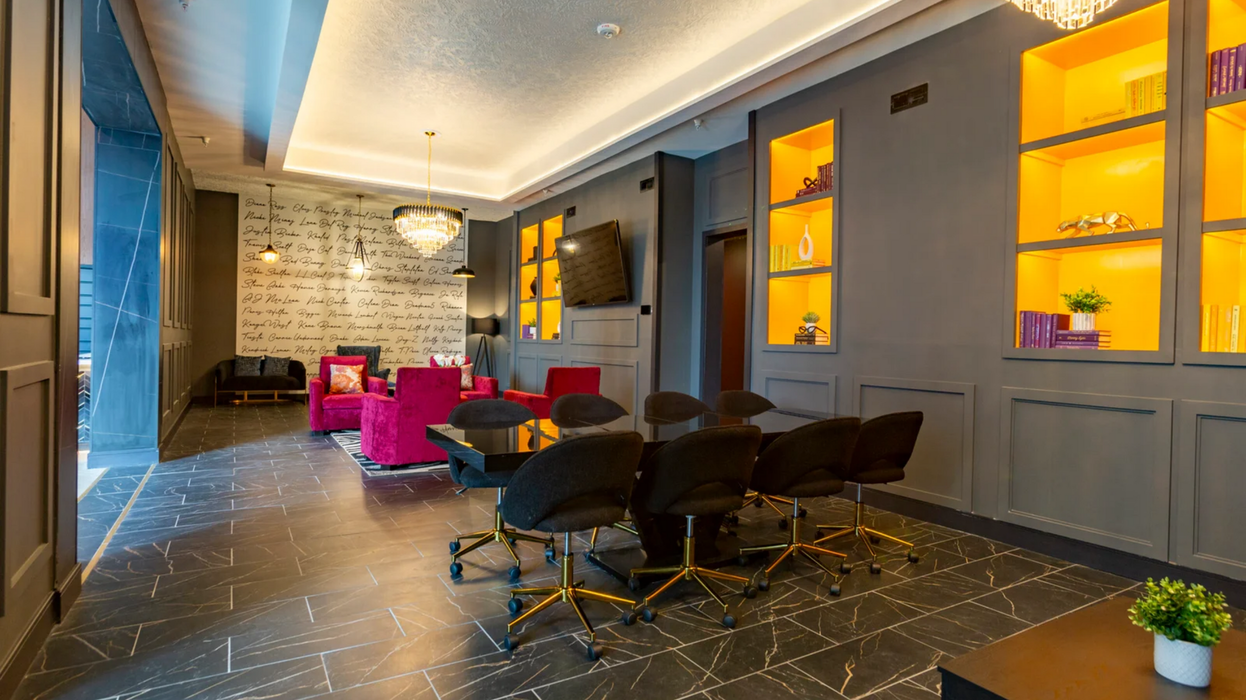 Elegant modern lounge with vibrant pink seating, sleek black table, and illuminated shelving, ideal for luxurious gatherings.