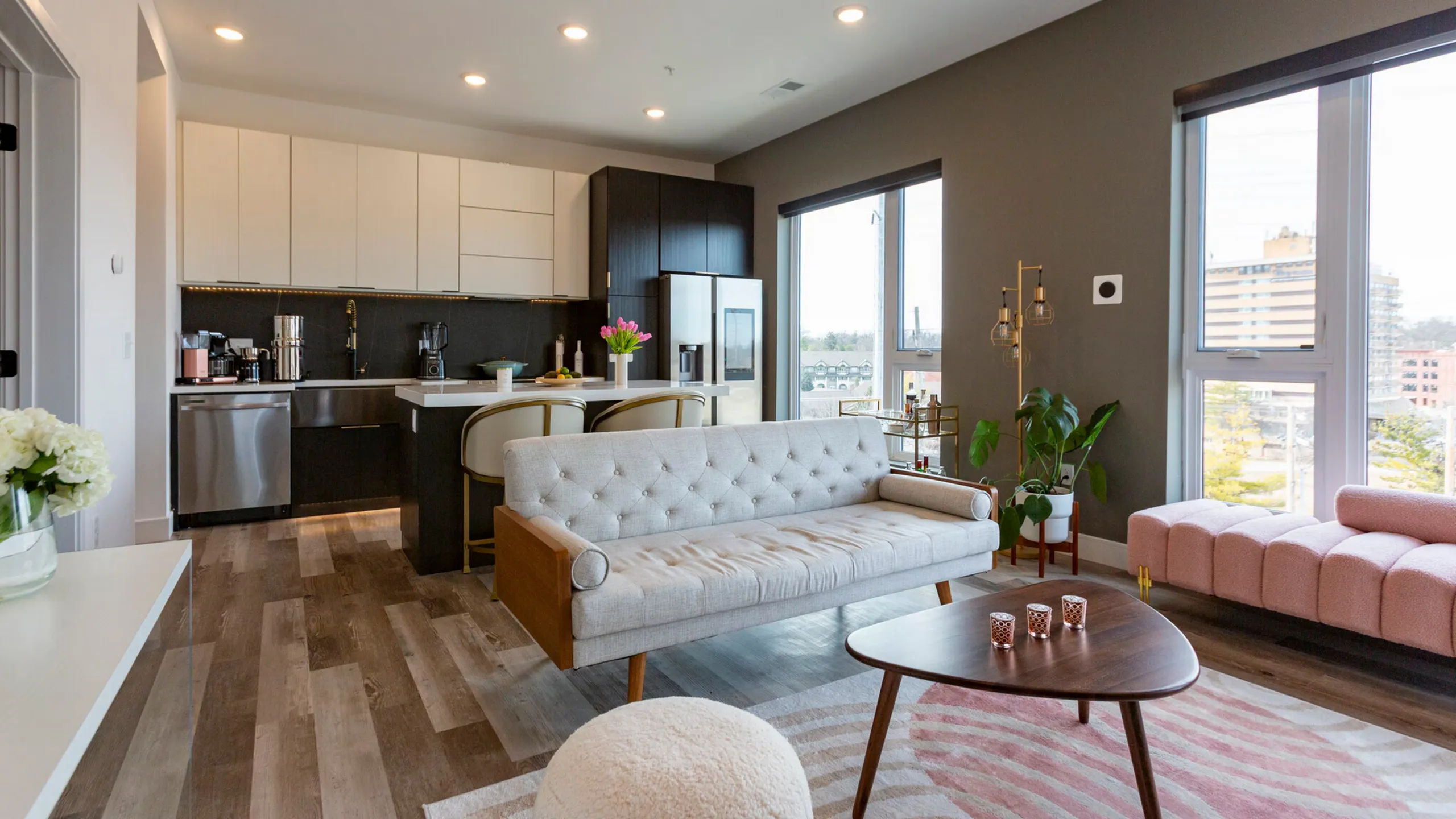 Modern open-concept apartment with a sleek kitchen, cozy living area, and expansive city views through large windows.