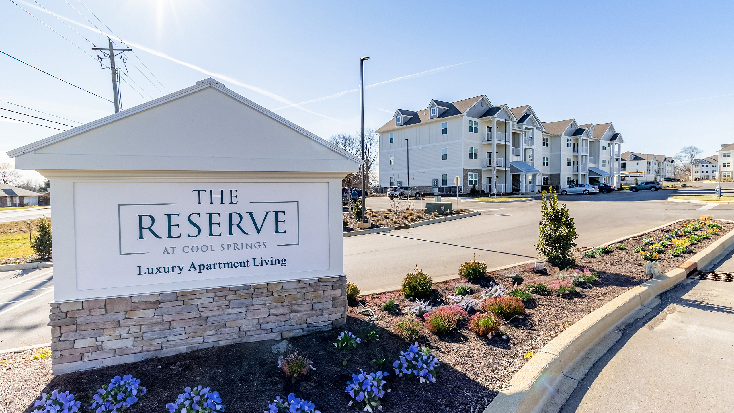 Inviting exterior of The Reserve at Cool Springs, showcasing luxury apartment living with manicured landscaping and spacious parking.