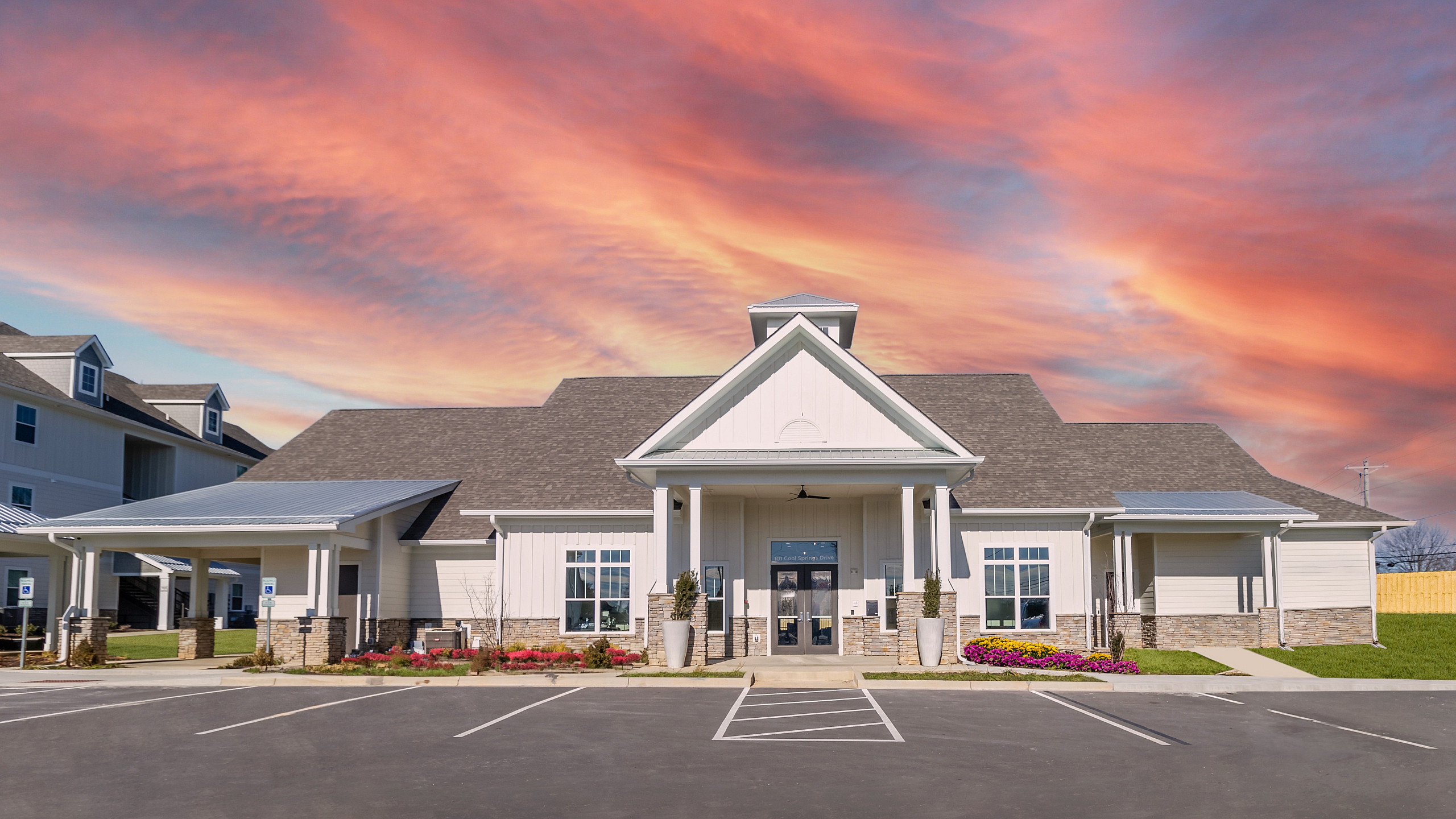 Inviting apartment complex exterior with classic architecture, vibrant landscaping, and a gorgeous sunset backdrop.