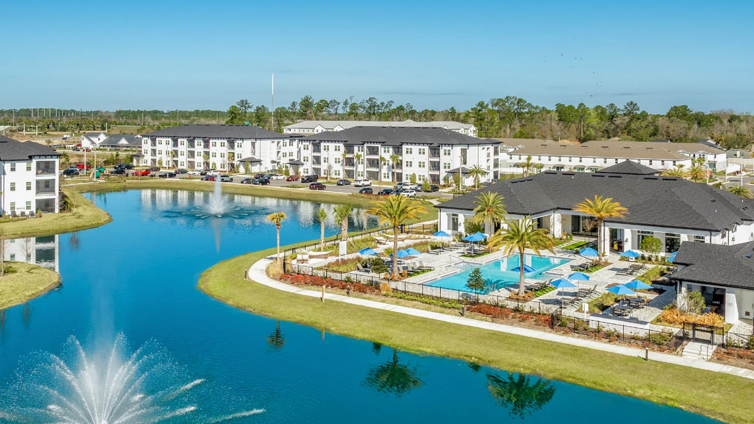 Luxurious lakeside apartment complex featuring lush landscaping, pristine swimming pool, and elegant modern architecture.