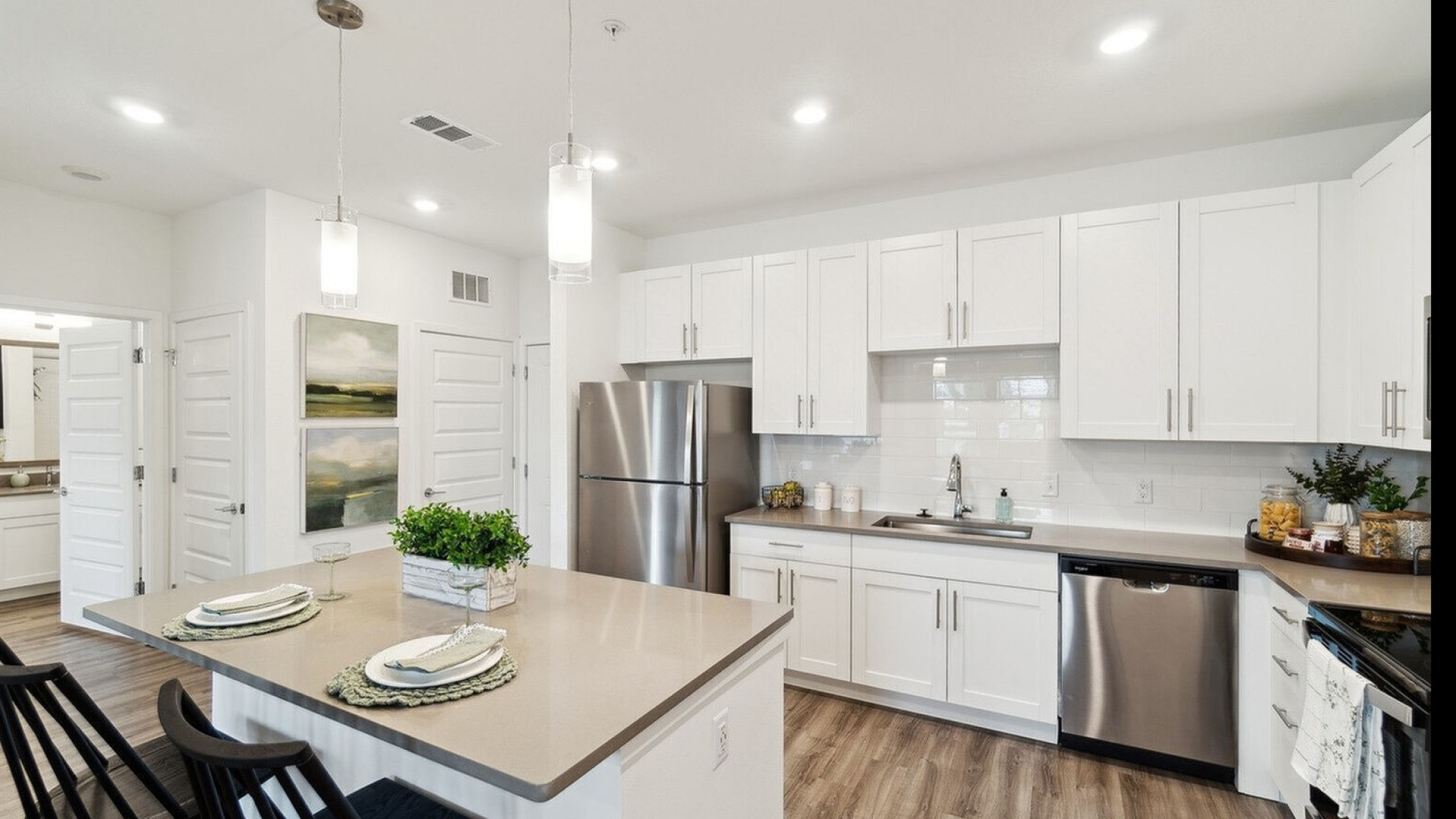 Bright modern kitchen with sleek white cabinetry, stainless steel appliances, and elegant pendant lighting over a stylish island with bar seating.