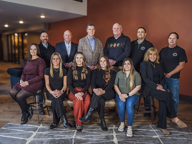 A diverse team of professionals posed confidently in a modern office setting, showcasing unity and expertise. Warm lighting highlights their approachable smiles.