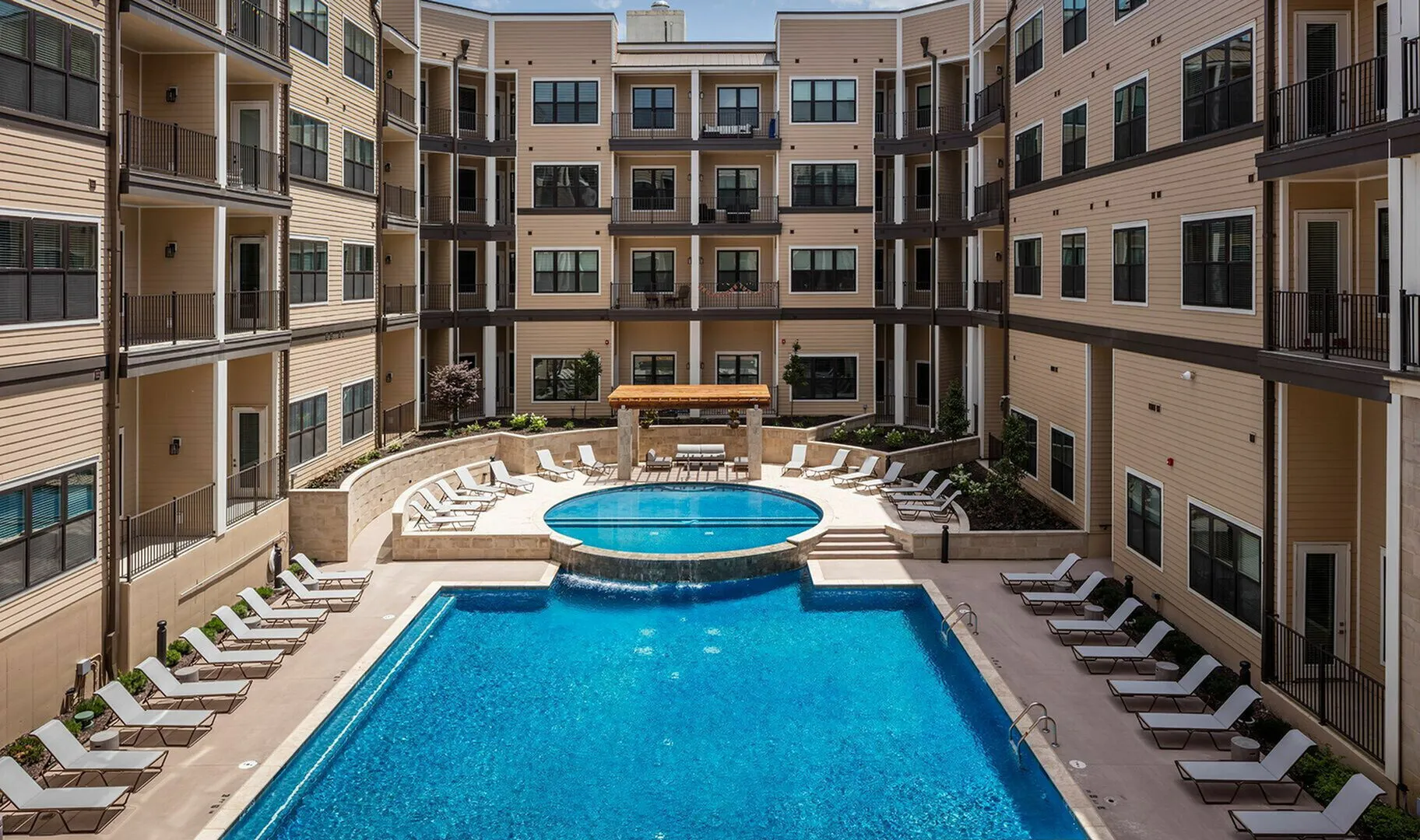 Luxurious apartment complex featuring a pristine swimming pool and stylish lounge chairs, surrounded by modern balconies.