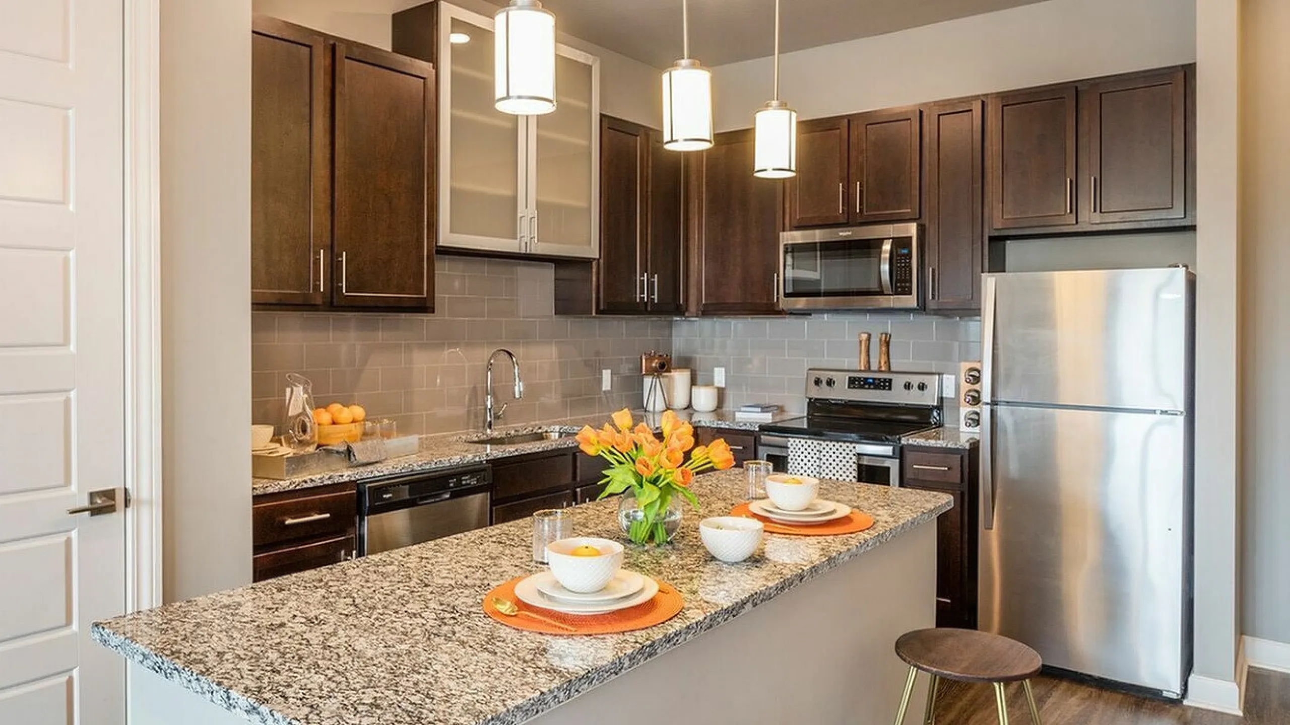 Modern kitchen with elegant granite countertops, stainless steel appliances, and pendant lighting over a stylish breakfast bar.