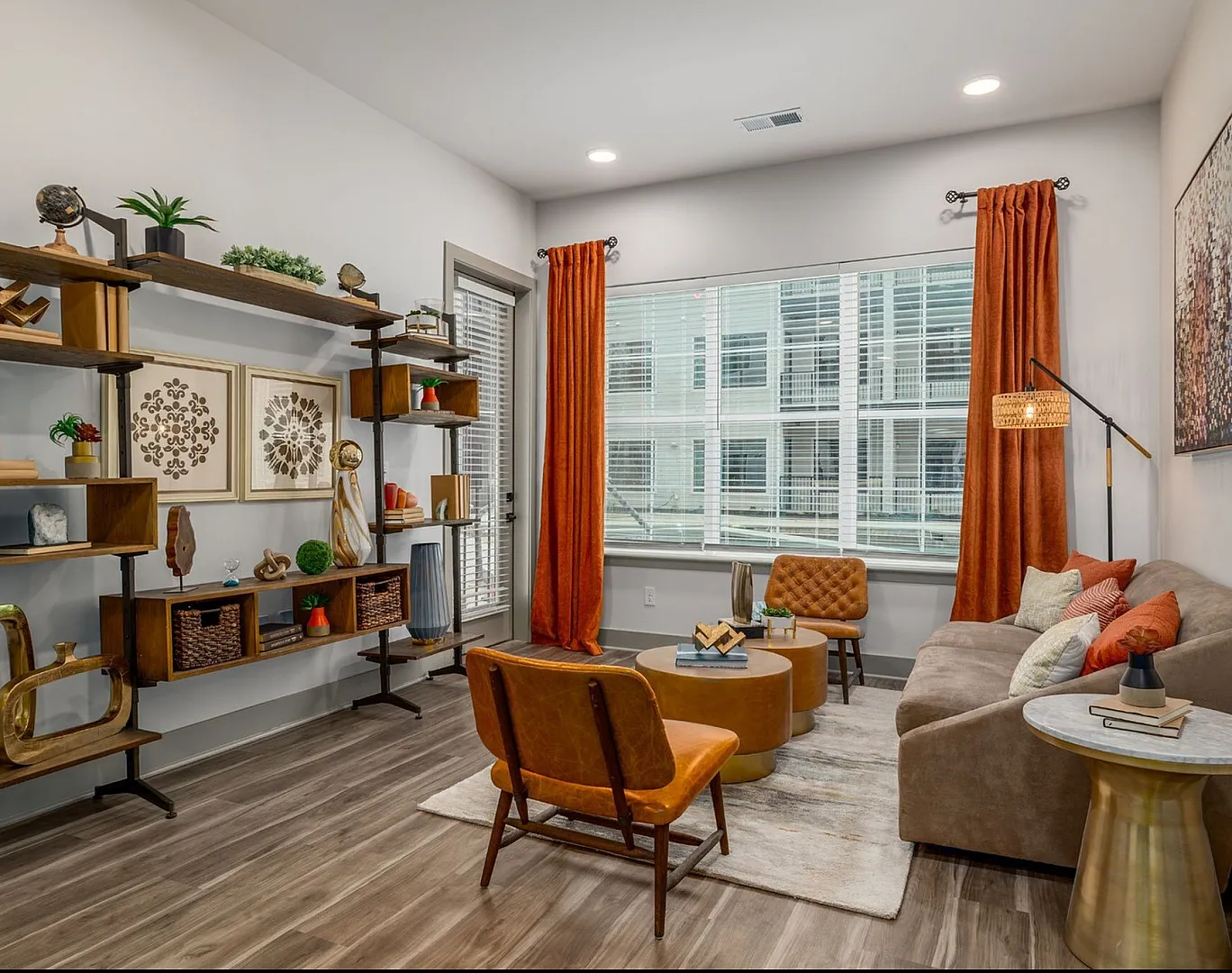 Chic and modern living room with elegant decor, featuring cozy seating, vibrant orange curtains, and stylish shelving in a well-lit space.
