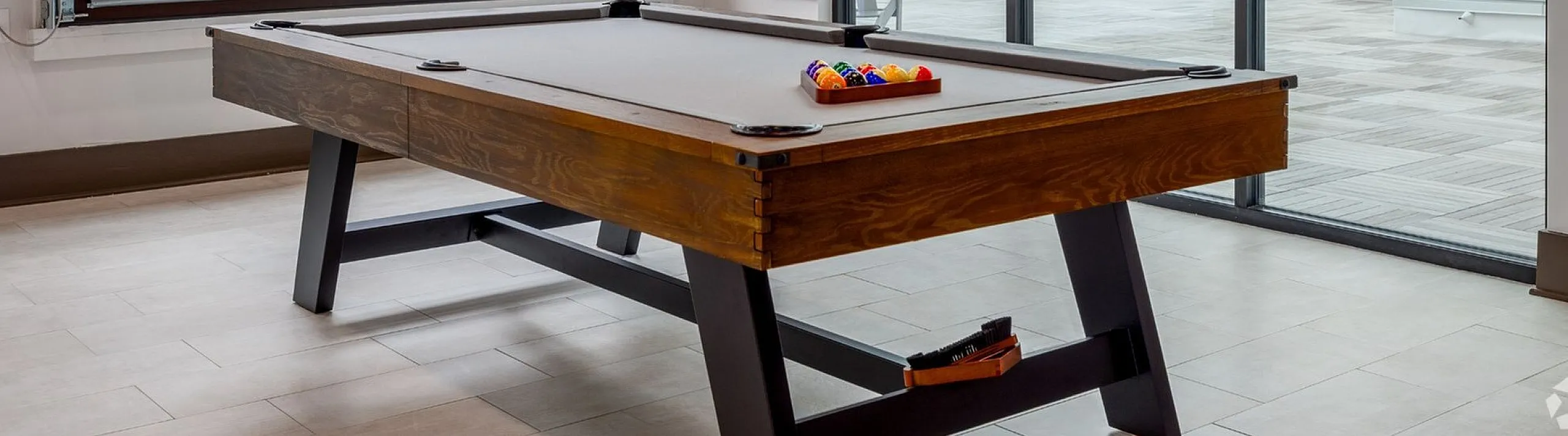 Chic apartment recreation area featuring a premium billiards table, stylish lighting, and large windows with courtyard views, perfect for leisure and socializing.