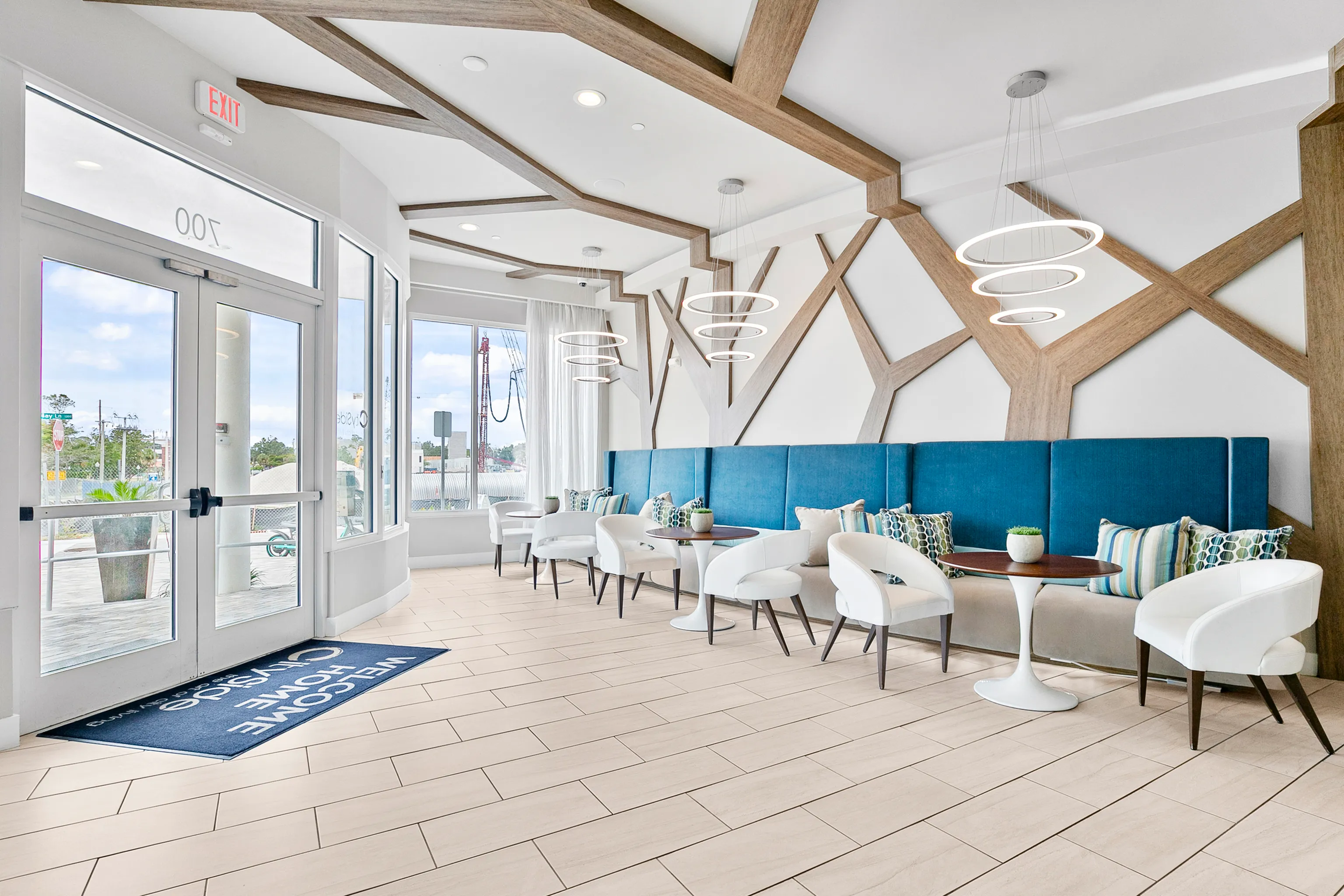 Modern lobby with stylish seating and geometric ceiling design, featuring elegant pendant lighting and a bright, welcoming atmosphere.