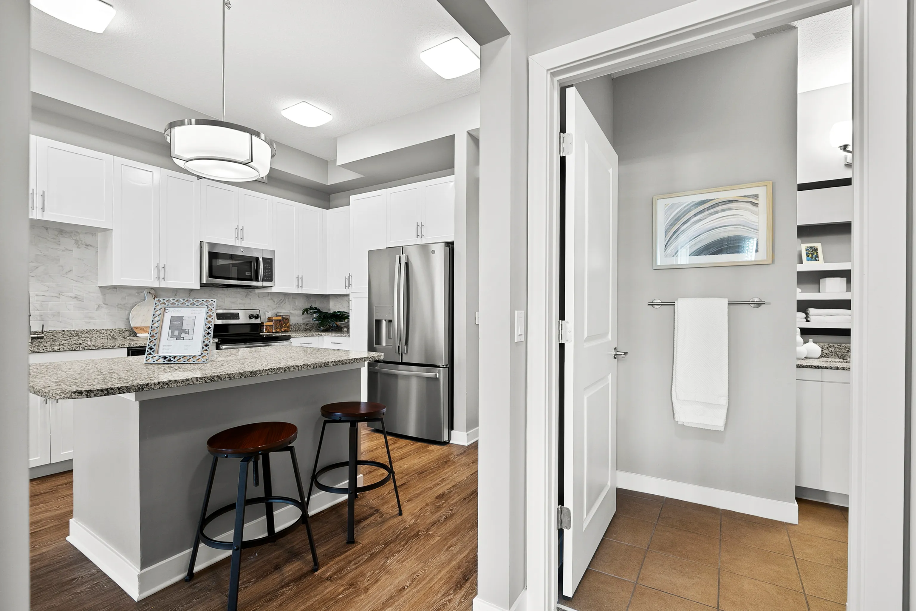 Elegant modern kitchen featuring sleek white cabinetry, granite countertops, stainless steel appliances, and a cozy breakfast bar with chic bar stools.