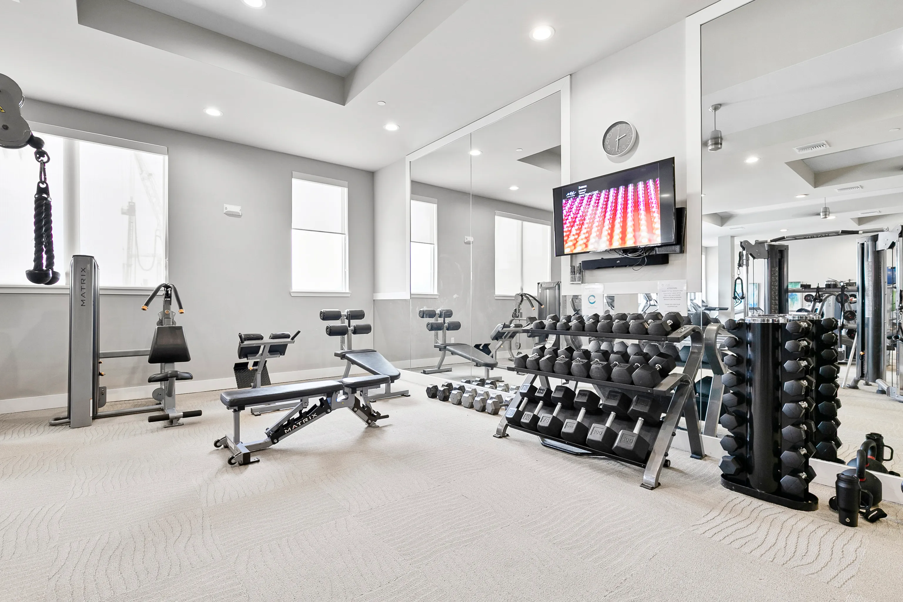 Modern apartment gym with state-of-the-art equipment, ample natural light, and sleek workout space.