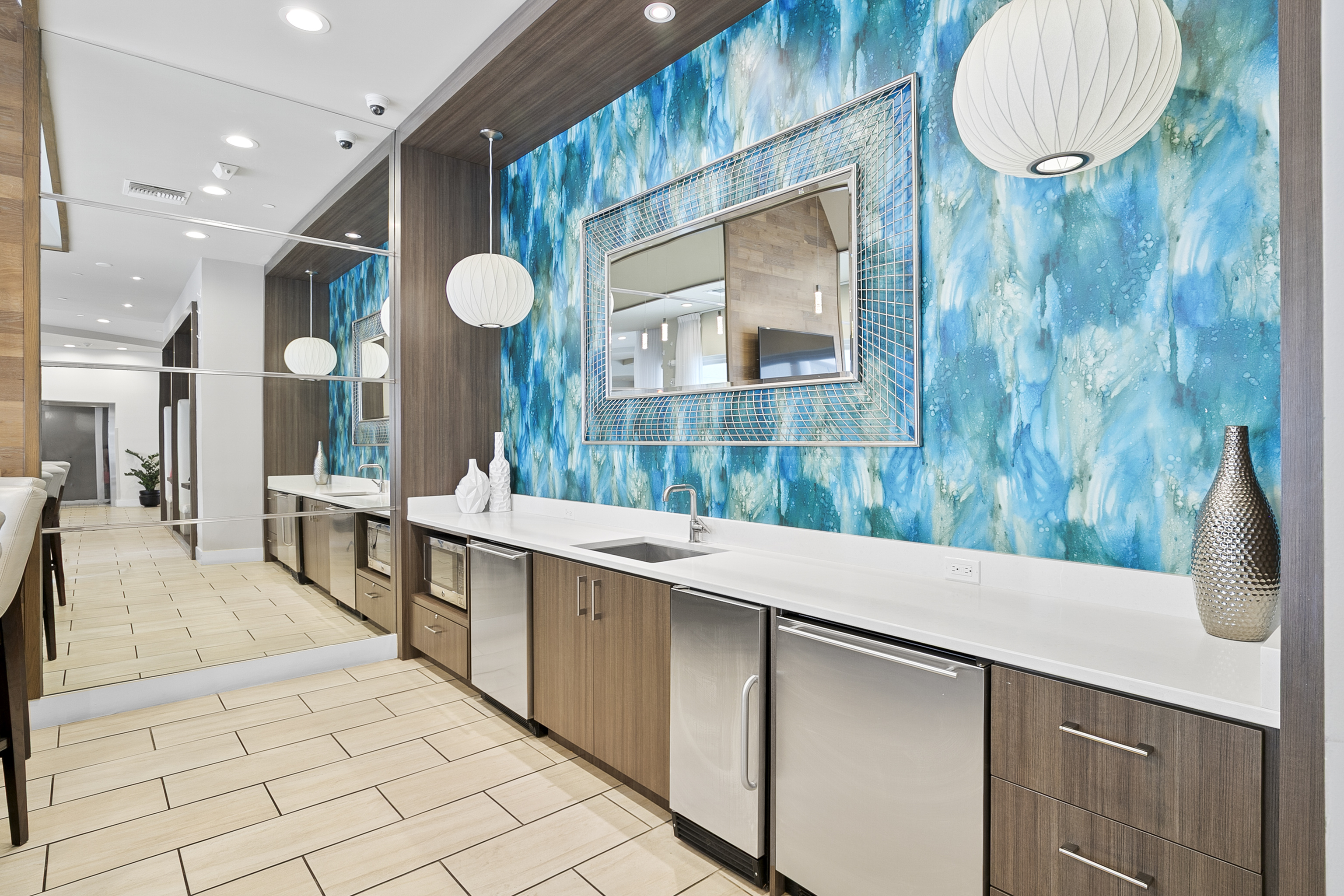 Modern kitchen area with elegant wood cabinets, a vibrant teal backsplash, and sleek stainless steel appliances, creating a contemporary and inviting ambiance.
