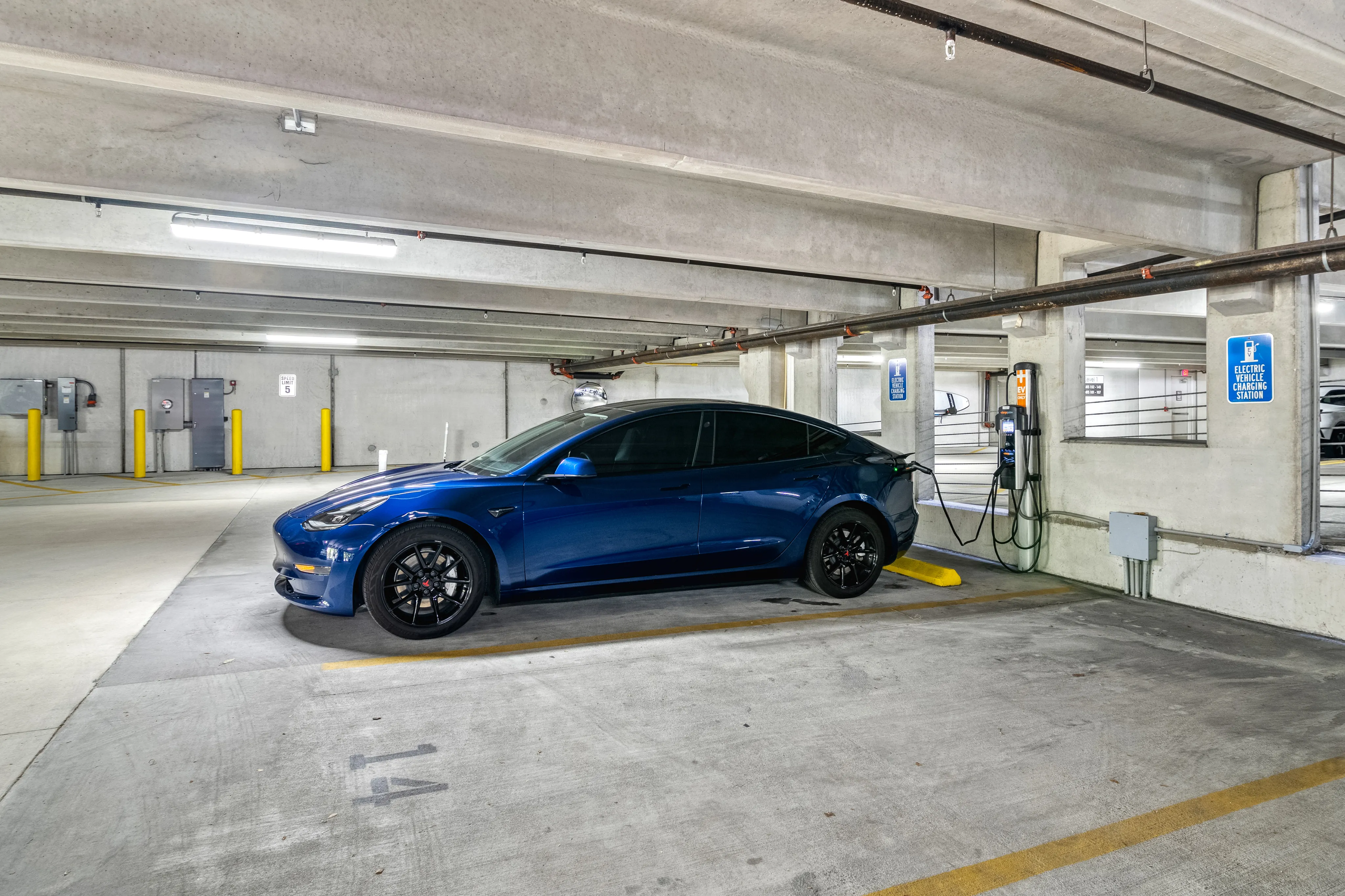 Modern parking facility featuring an electric vehicle charging station with a sleek blue car, offering convenience and sustainability.