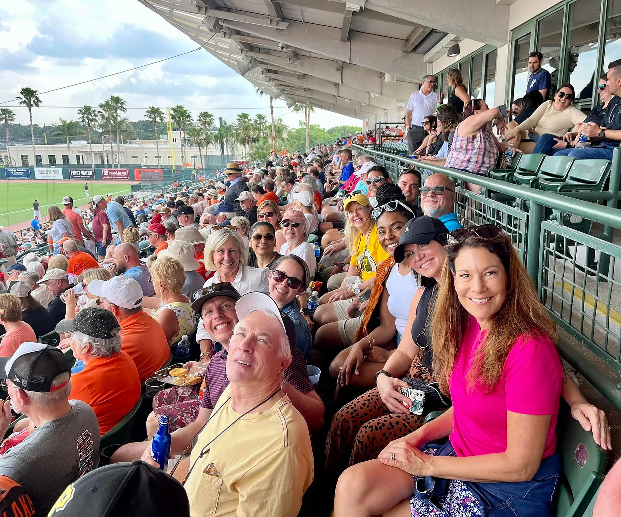 Vibrant baseball game crowd enjoying a sunny day at the stadium, surrounded by palm trees and a lively atmosphere.