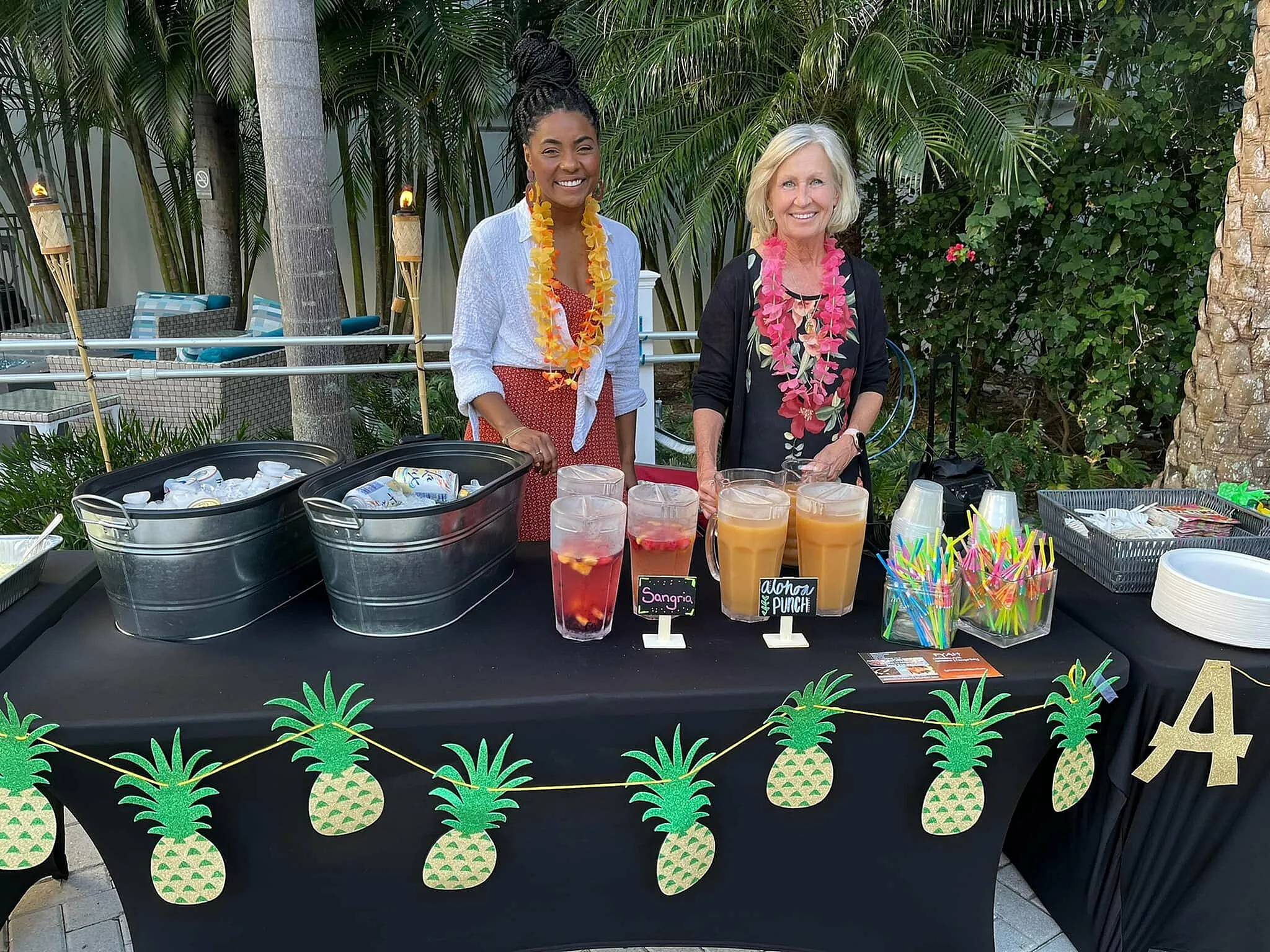 Tropical-themed refreshment stand with two smiling individuals, featuring colorful drinks, bright decorations, and vibrant atmosphere.