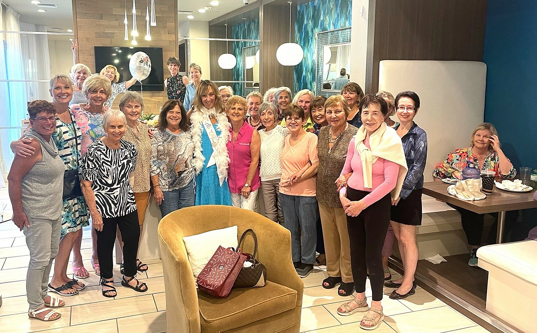Cheerful gathering of smiling women in a modern, inviting lounge with chic decor, cozy seating, and ambient lighting.