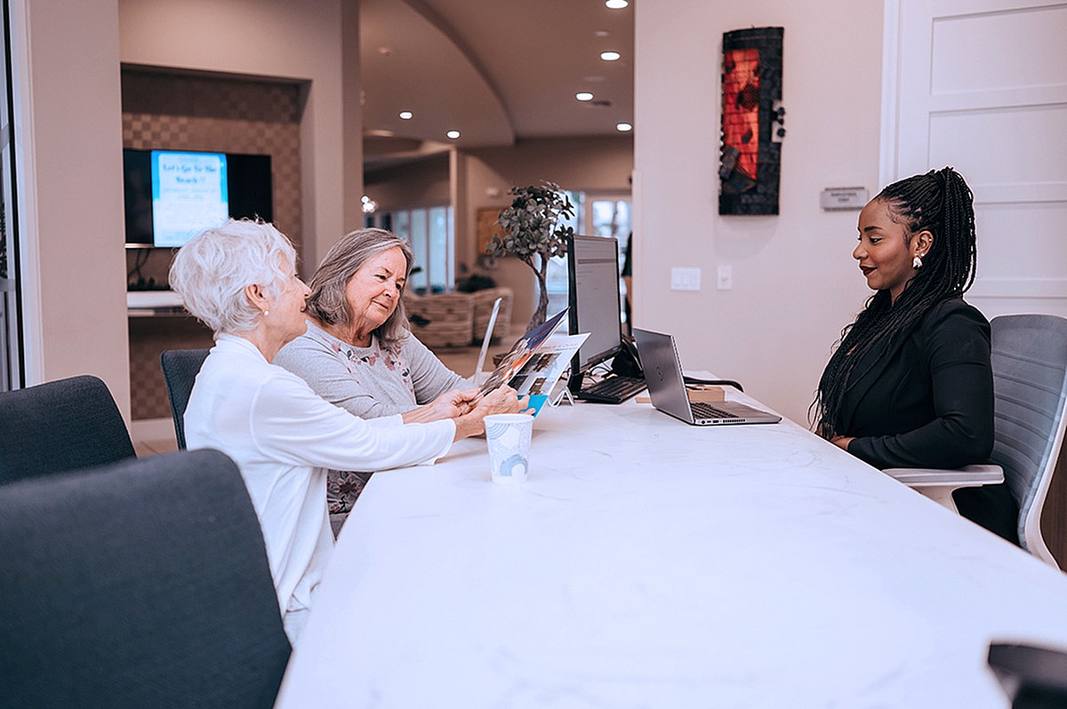 Welcoming modern office consultation with two smiling clients and an attentive professional, enhancing customer service experience.