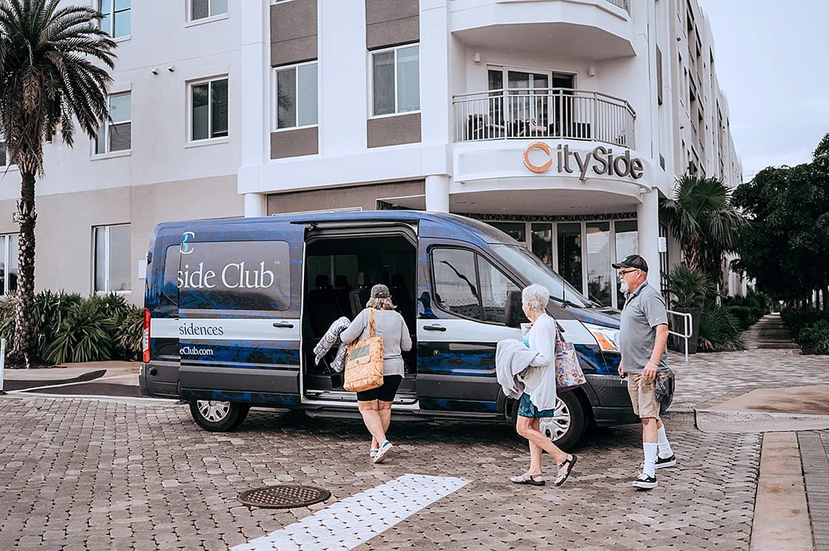 Welcoming entrance of CitySide Residences with guests boarding a stylish club van, surrounded by lush greenery.