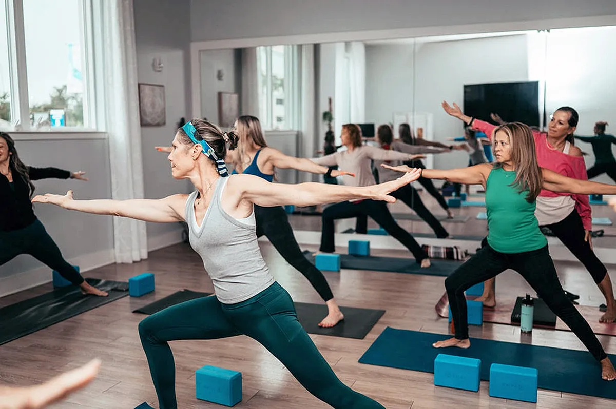 Inviting yoga studio with a group of women practicing vibrant poses, surrounded by mirrors and natural light.