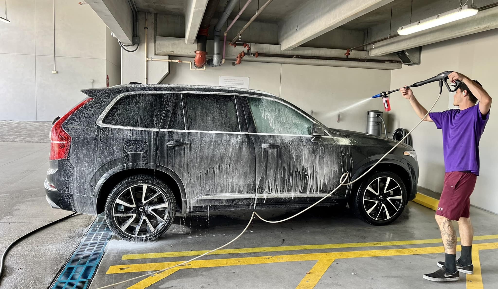 Effortless car washing in a spacious parking area, highlighting efficient cleaning with a hose and foamy lather.