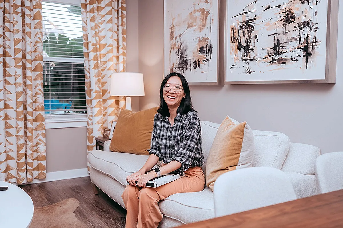 Bright and cozy living room with modern art, plush pillows, and elegant curtains framing a scenic window view.| City Side Apartments | Sarasota, FL