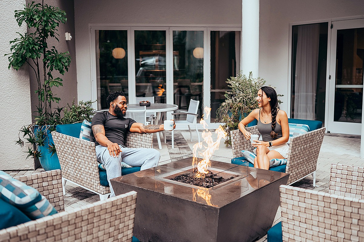 Chic outdoor patio with a cozy fire pit, comfortable seating, and people enjoying a relaxed coffee conversation. | City Side Apartments | Sarasota, FL