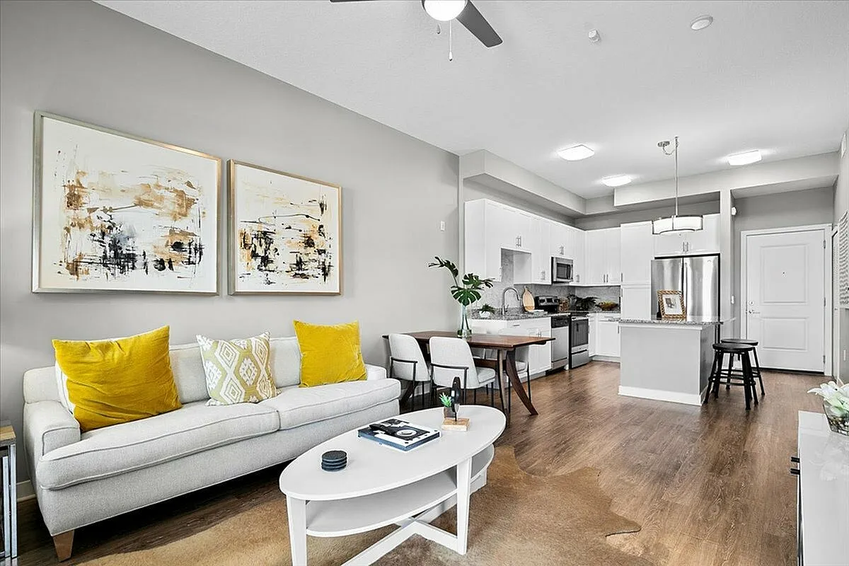 Modern open-concept living room with cozy seating, chic decor, and a sleek kitchen featuring stainless steel appliances. | City Side Apartments | Sarasota, FL