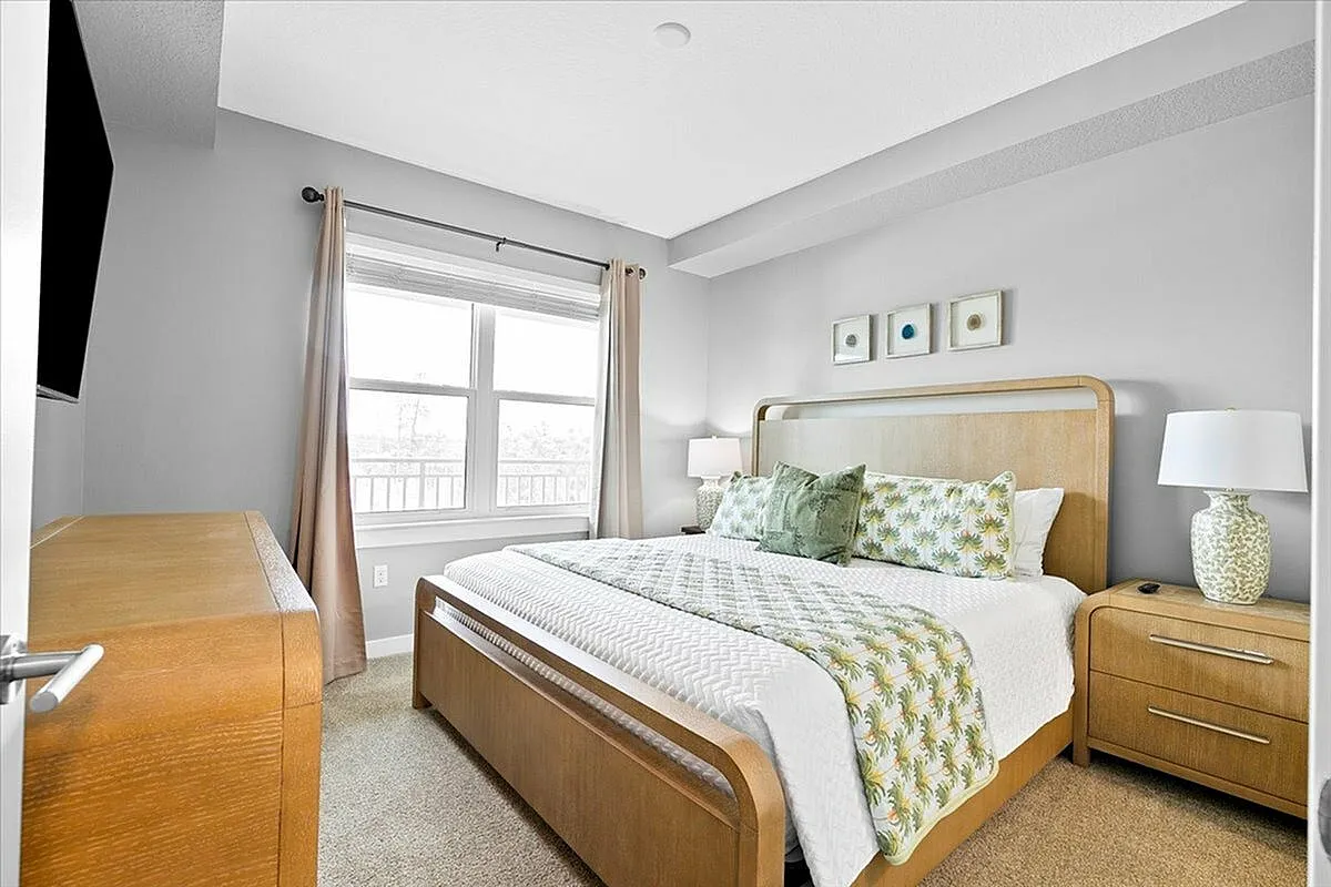 Bright and inviting bedroom featuring a stylish wooden bed with patterned bedding, modern dresser, and natural light from a large window. | City Side Apartments | Sarasota, FL