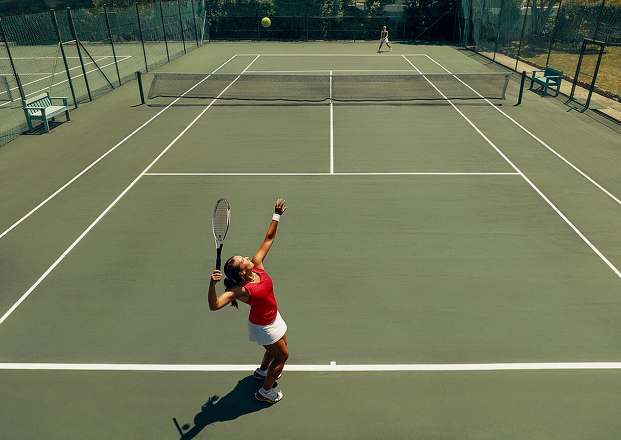 Dynamic tennis match on a sunlit outdoor court with players in action, showcasing athleticism and competitive spirit.