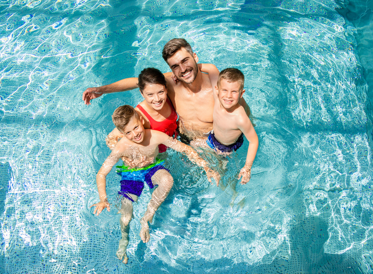 Cheerful family enjoying a sunny day in a sparkling blue swimming pool, perfect for relaxation and leisure.