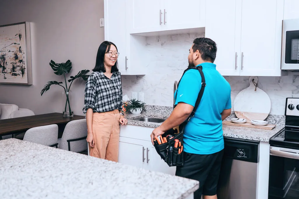 Modern kitchen interior with granite countertops, elegant cabinetry, and two people conversing, creating a welcoming atmosphere.