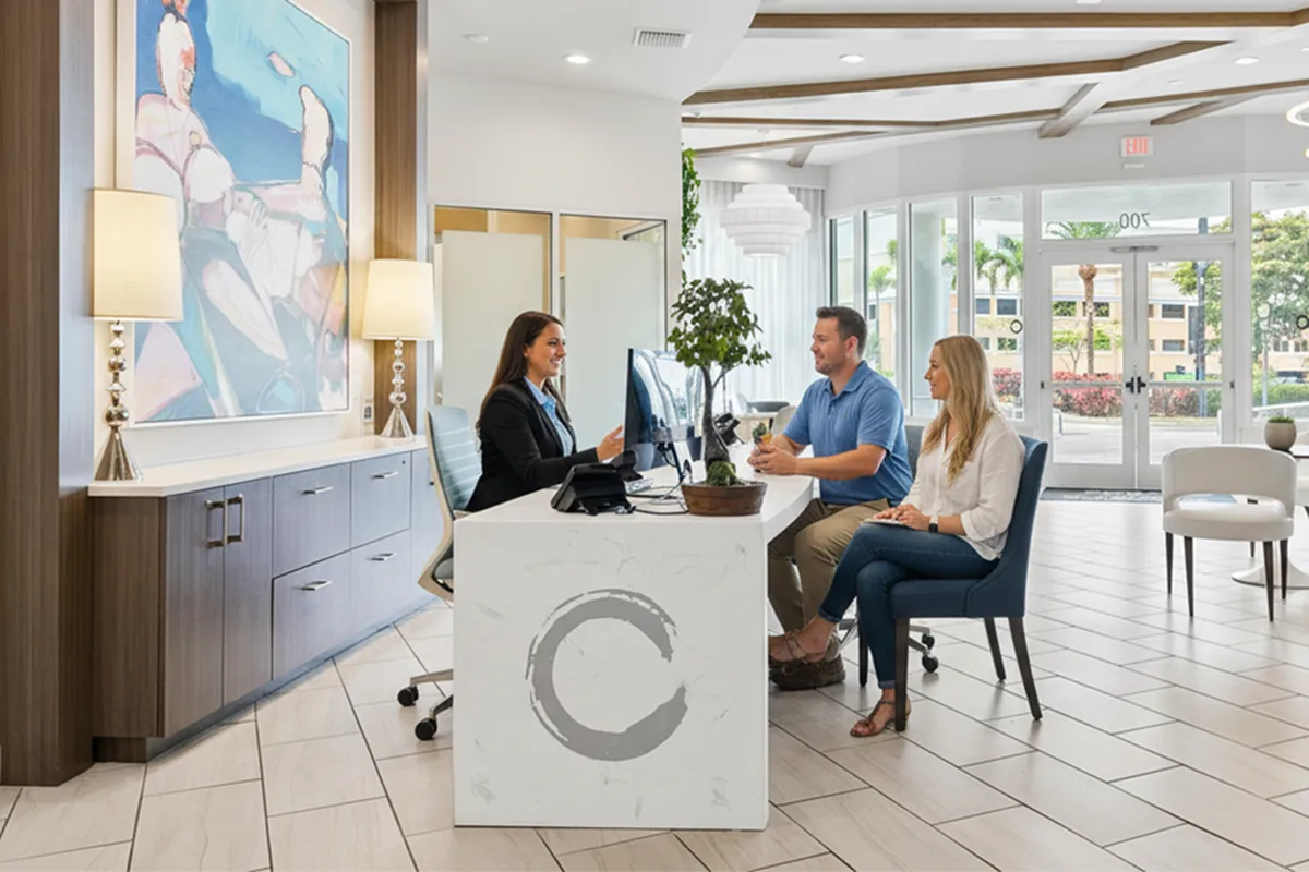 Welcoming leasing office lobby with friendly staff assisting clients, featuring modern decor and abundant natural light.