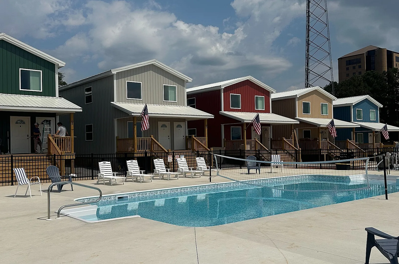Charming row of colorful houses with inviting outdoor pool and lounge chairs under a bright blue sky.
