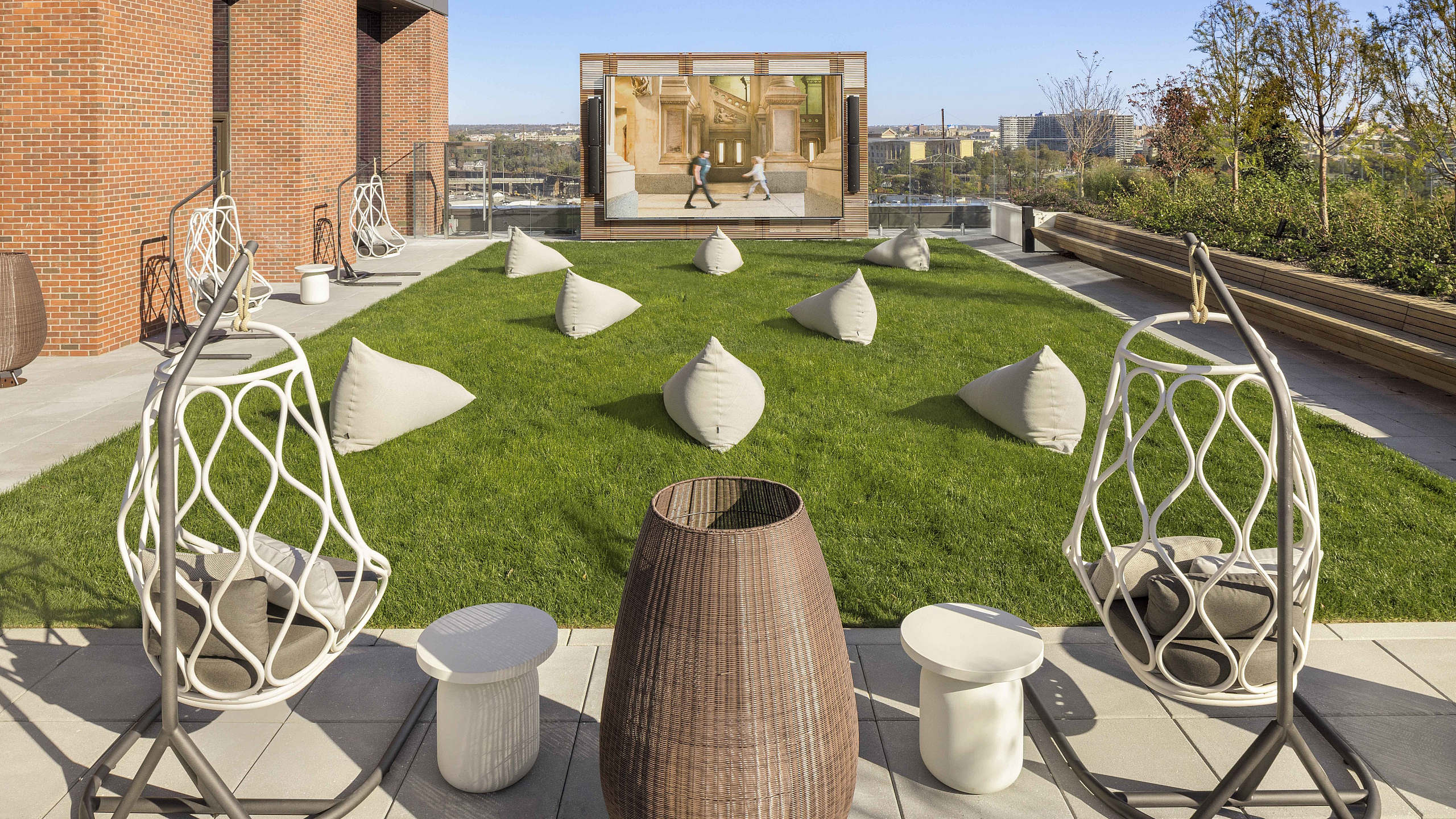 Luxurious rooftop garden with stylish egg chairs, lush grass, modern outdoor seating, and panoramic view.