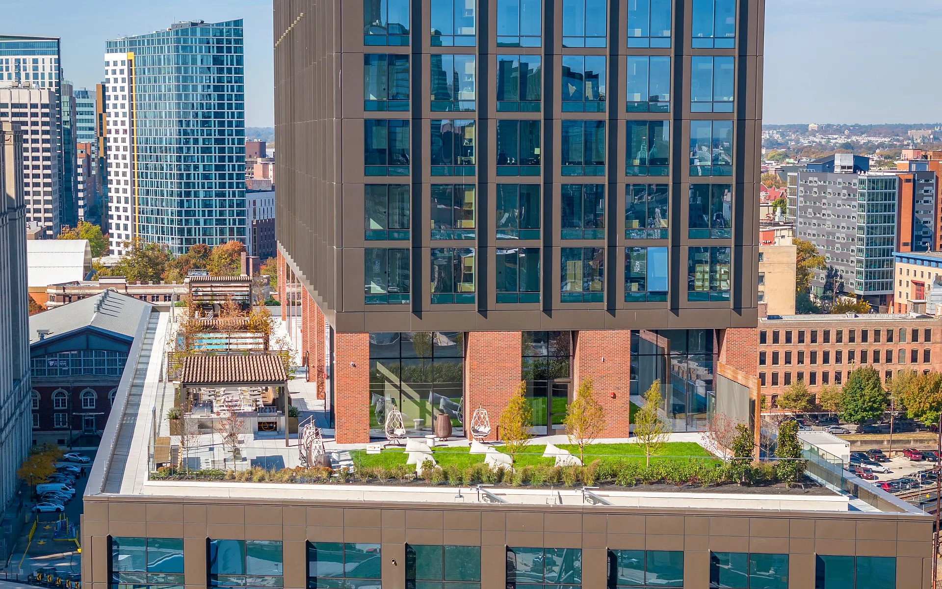 Modern cityscape view showcasing a sleek high-rise building with rooftop gardens and lush greenery, set against a vibrant urban skyline.