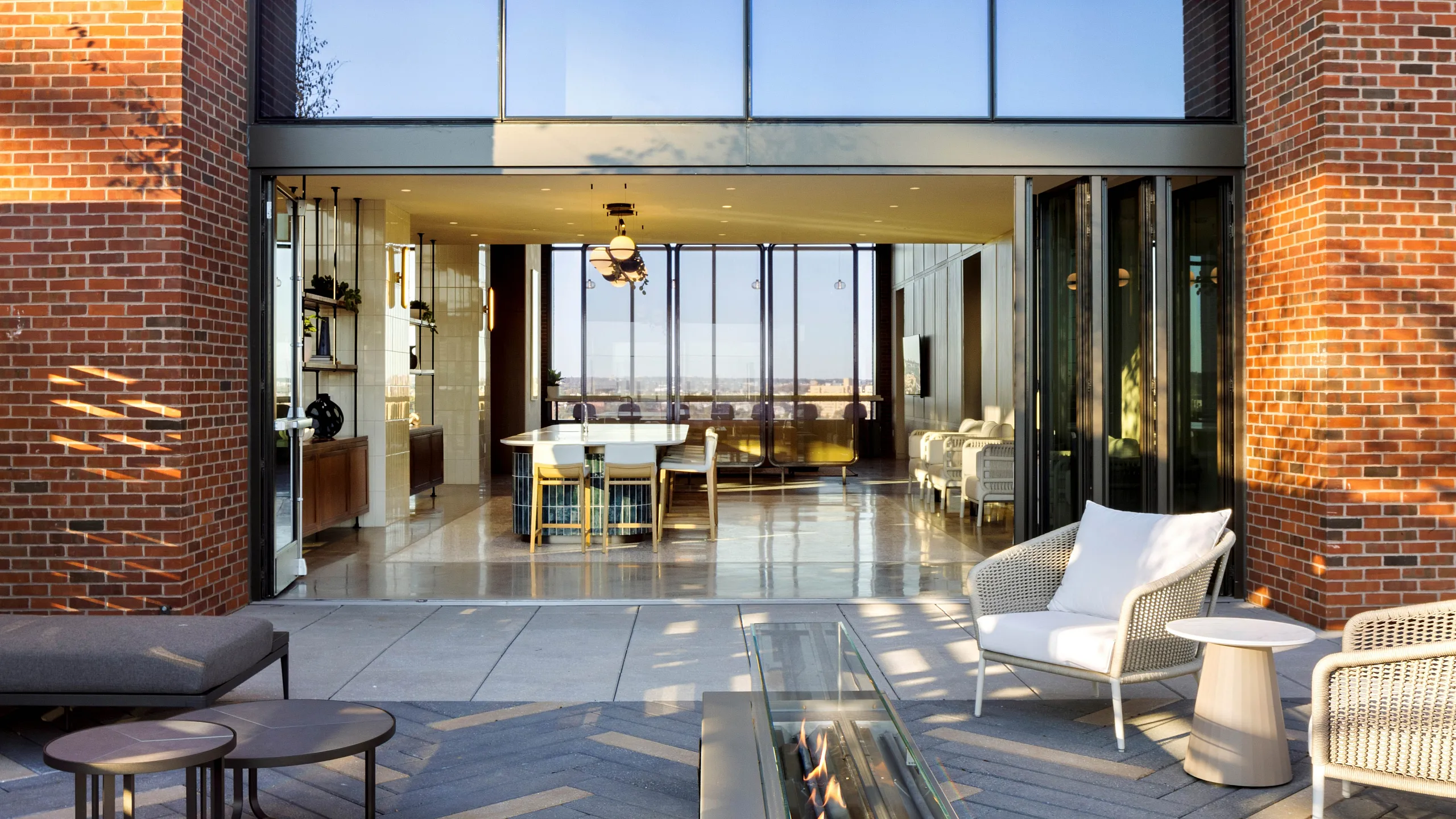 Modern open-concept apartment with expansive glass walls, cozy outdoor seating, and elegant indoor dining area.