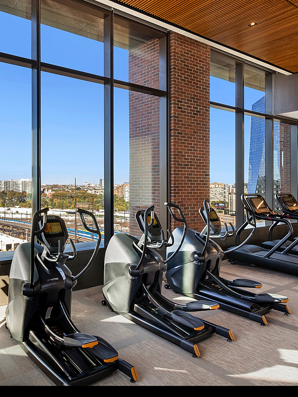 Luxurious fitness center with panoramic city views, featuring modern treadmills, elliptical machines, and stationary bikes.