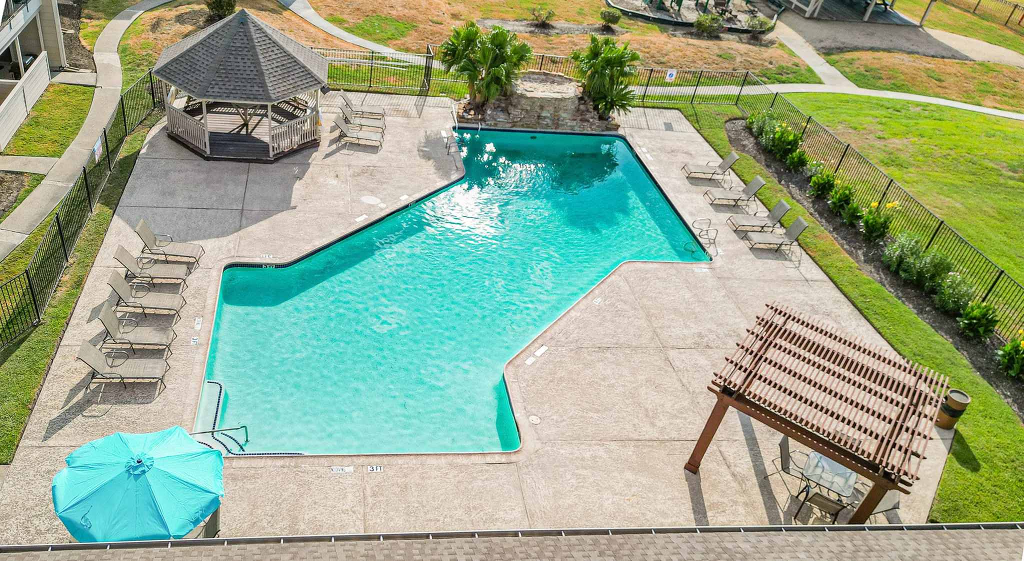 Inviting aerial view of a sparkling swimming pool with sun loungers, gazebo, and lush green surroundings, perfect for relaxing and enjoying outdoor living.
